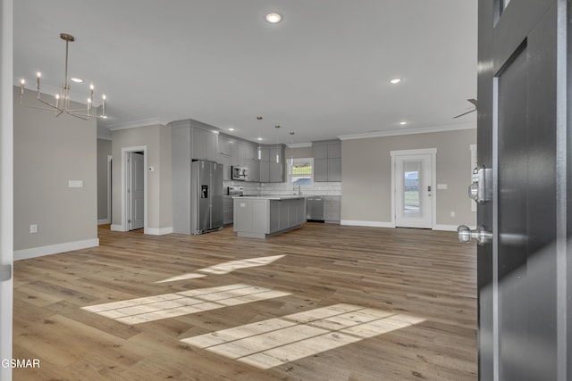 kitchen featuring gray cabinetry, stainless steel appliances, decorative light fixtures, a center island, and light hardwood / wood-style floors