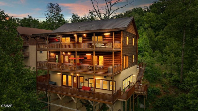2864 Owens Ridge Way, Sevierville, TN 37876 - back of property at dusk featuring a balcony, metal roof, stucco siding, and an attached garage