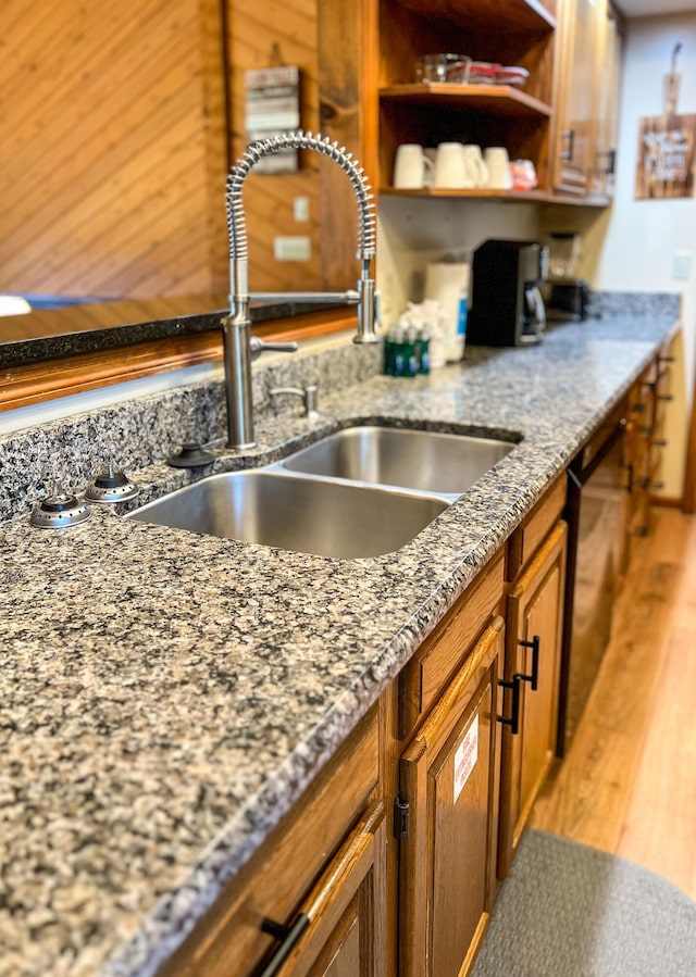 kitchen featuring dark stone countertops, dishwasher, and sink