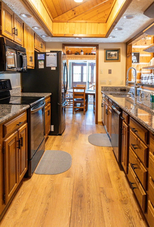 kitchen featuring wooden ceiling, black appliances, sink, dark stone countertops, and light wood-type flooring