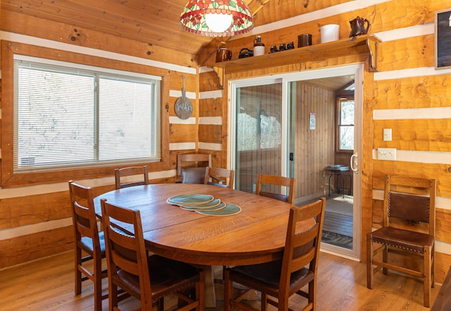 dining space featuring hardwood / wood-style flooring, lofted ceiling, and wooden walls