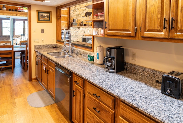 kitchen featuring light stone counters, sink, light hardwood / wood-style flooring, and black dishwasher