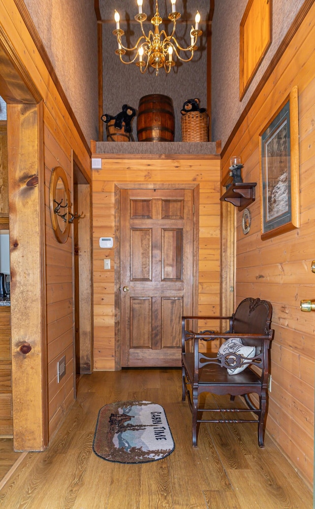 foyer with wooden walls, a chandelier, and hardwood / wood-style flooring