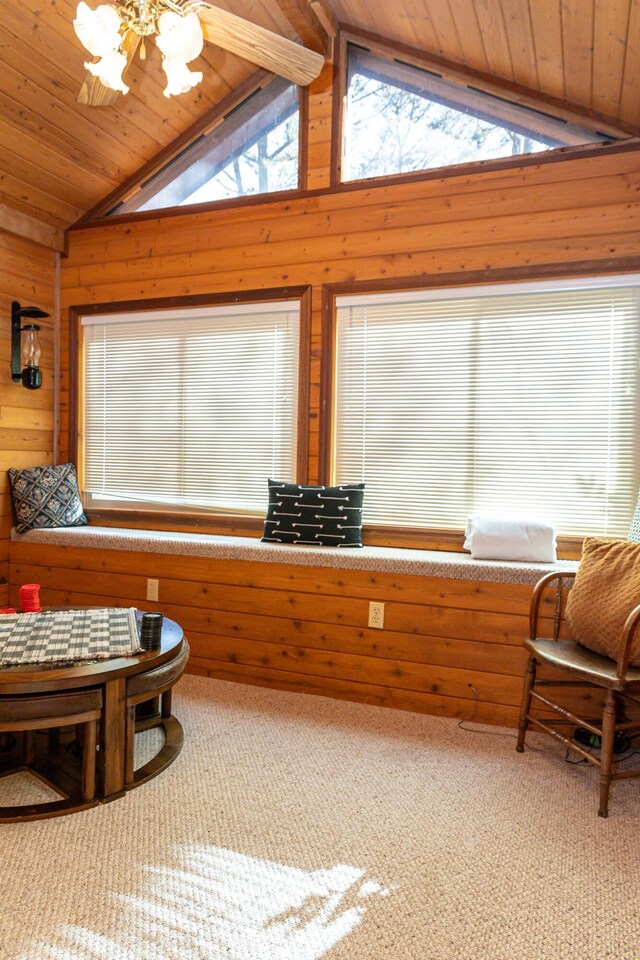 living area with carpet flooring, wooden walls, ceiling fan, and lofted ceiling