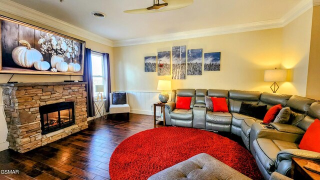 living room with crown molding, dark hardwood / wood-style flooring, and a stone fireplace