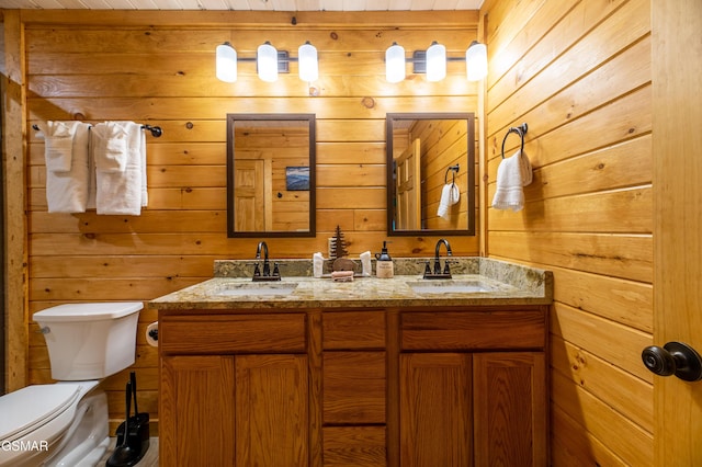 bathroom featuring vanity, toilet, and wooden walls