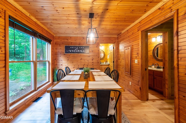 dining area with light wood-type flooring, wood walls, and wood ceiling