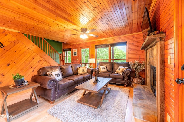 living room with ceiling fan, wooden walls, and wood ceiling