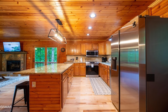 kitchen featuring a kitchen breakfast bar, decorative light fixtures, light stone counters, and stainless steel appliances