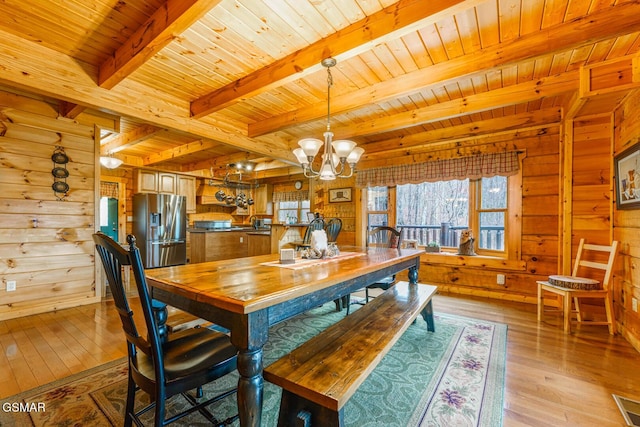 dining area featuring light wood-style floors, wood walls, and an inviting chandelier