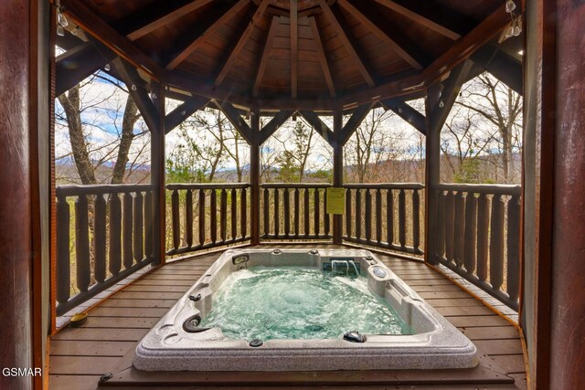 deck featuring hot tub deck surround and a gazebo