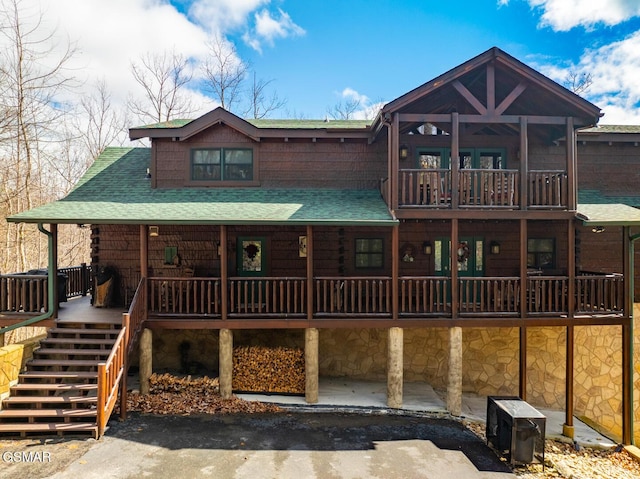 view of front of home featuring stone siding, a shingled roof, and stairs