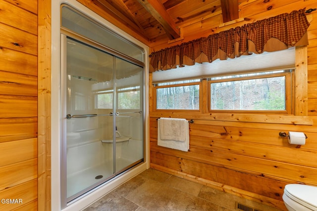 bathroom featuring a stall shower, plenty of natural light, wooden walls, and toilet