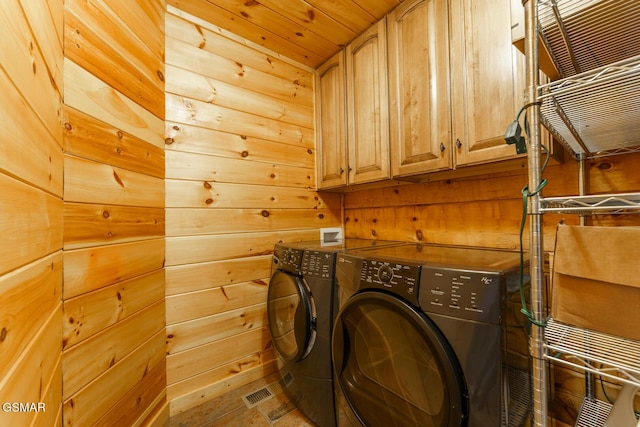 laundry room featuring cabinet space, wooden walls, visible vents, and washer and dryer