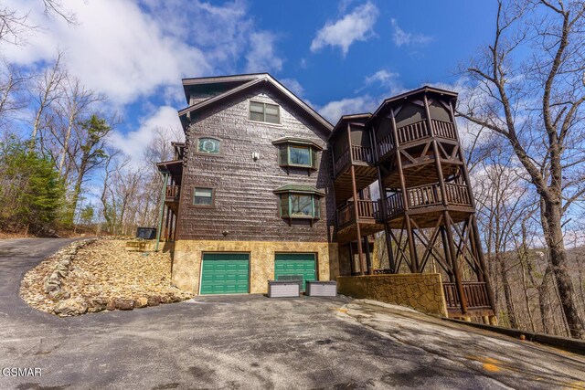 exterior space featuring a garage, aphalt driveway, and a balcony