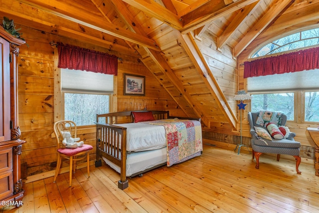 bedroom with lofted ceiling with beams, wood walls, and light wood finished floors