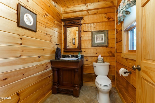 bathroom featuring vanity, toilet, and wooden walls