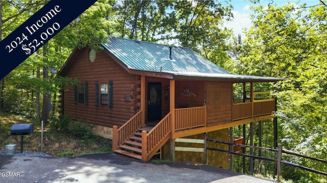 view of front of house featuring a porch, metal roof, and log siding