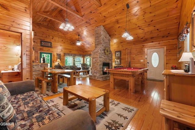 living area with wooden walls, high vaulted ceiling, plenty of natural light, light wood finished floors, and a ceiling fan