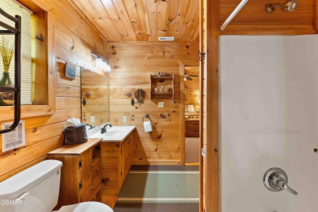 bathroom with wooden walls, wood ceiling, toilet, vanity, and  shower combination