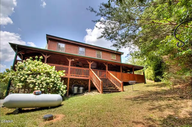 back of property with a yard, log veneer siding, a ceiling fan, and stairs