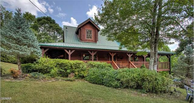 log home with log siding, metal roof, a front lawn, and a porch