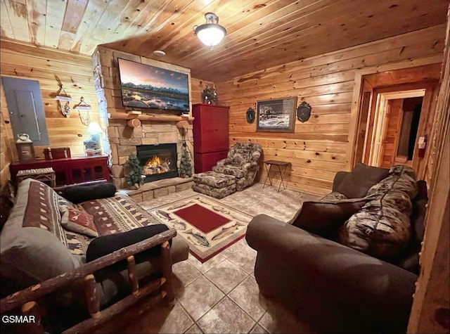 living area featuring wooden walls, tile patterned flooring, a stone fireplace, and wooden ceiling