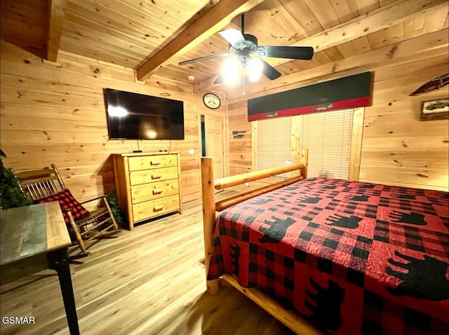 bedroom featuring wooden walls, wood finished floors, wooden ceiling with exposed beams, and a ceiling fan