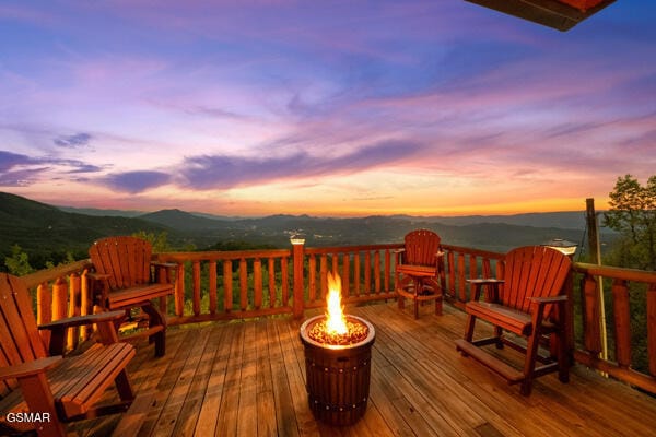 wooden deck featuring an outdoor fire pit and a mountain view