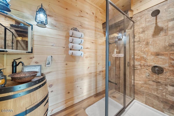 bathroom with wooden walls, vanity, and a stall shower