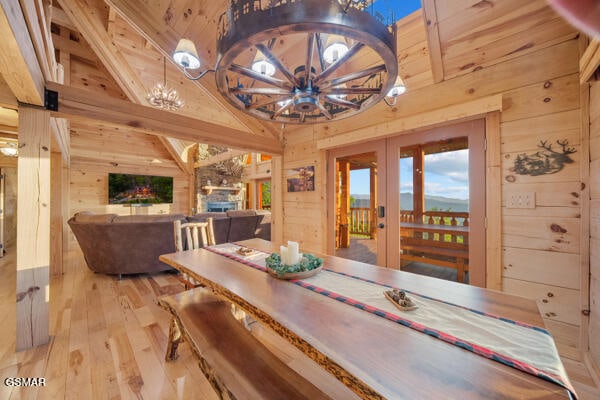 dining space featuring hardwood / wood-style flooring, wood walls, french doors, and an inviting chandelier