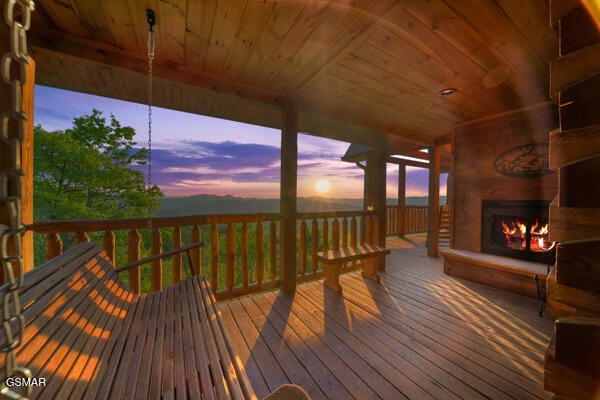 deck at dusk featuring a lit fireplace