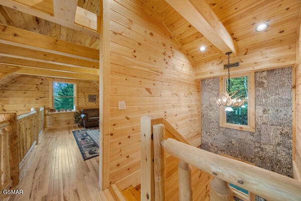 additional living space with wooden walls, a chandelier, hardwood / wood-style floors, vaulted ceiling with beams, and wood ceiling