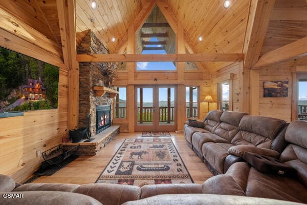 living room with wood walls, wood finished floors, a fireplace, high vaulted ceiling, and wooden ceiling