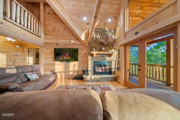 living room with wooden walls, high vaulted ceiling, wood ceiling, and wood finished floors