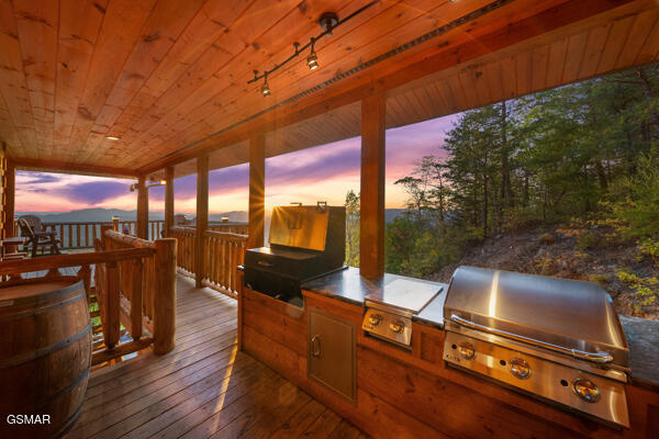 wooden deck with an outdoor kitchen and a grill