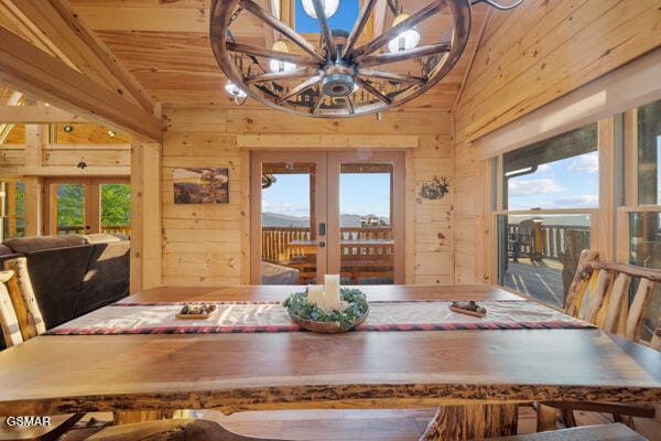unfurnished dining area featuring wooden walls, a healthy amount of sunlight, and french doors