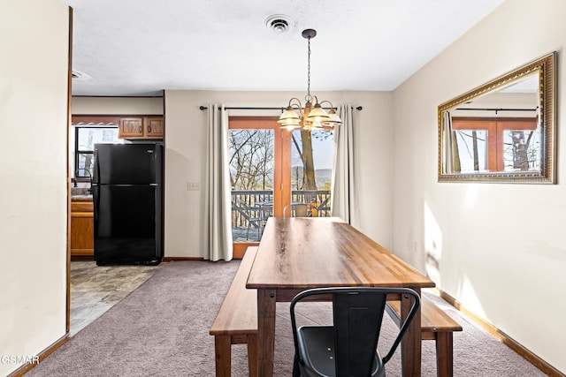 carpeted dining area with a notable chandelier and a healthy amount of sunlight