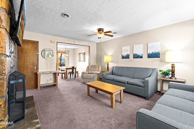 living room featuring ceiling fan, dark carpet, a textured ceiling, and a fireplace