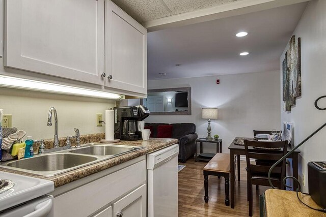 kitchen with wood-type flooring, white dishwasher, white cabinetry, and sink