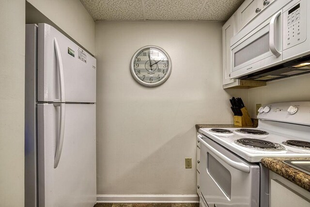 kitchen with a drop ceiling, white cabinets, and white appliances