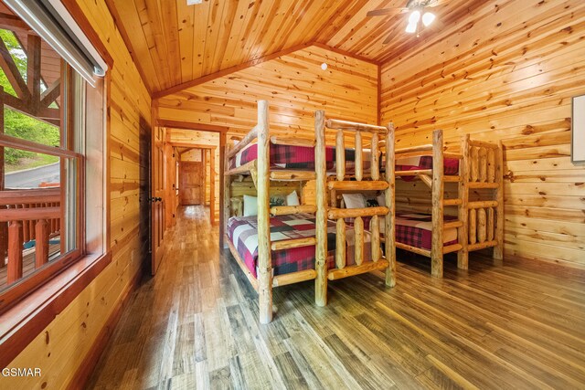 bedroom with wood finished floors, lofted ceiling, wooden walls, and wooden ceiling