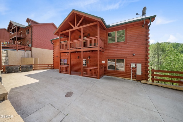 back of property with a patio, fence, log exterior, and a balcony