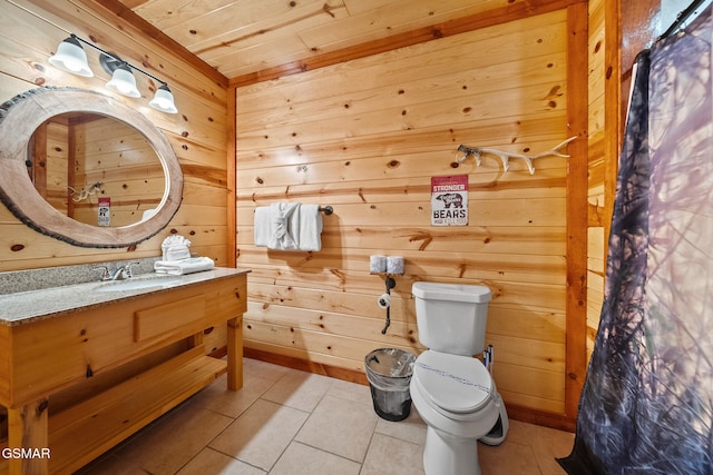 bathroom featuring toilet, tile patterned floors, wood walls, and vanity