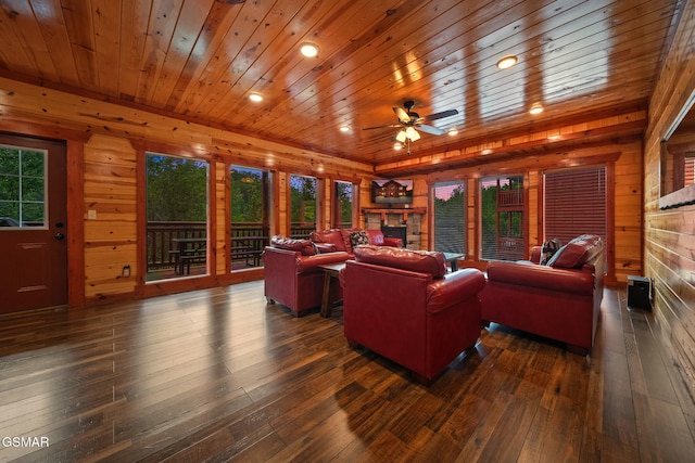 living area with wooden walls, ceiling fan, a stone fireplace, wooden ceiling, and hardwood / wood-style flooring