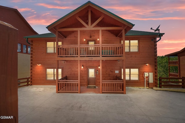 back of house with fence, log exterior, a balcony, and a patio area