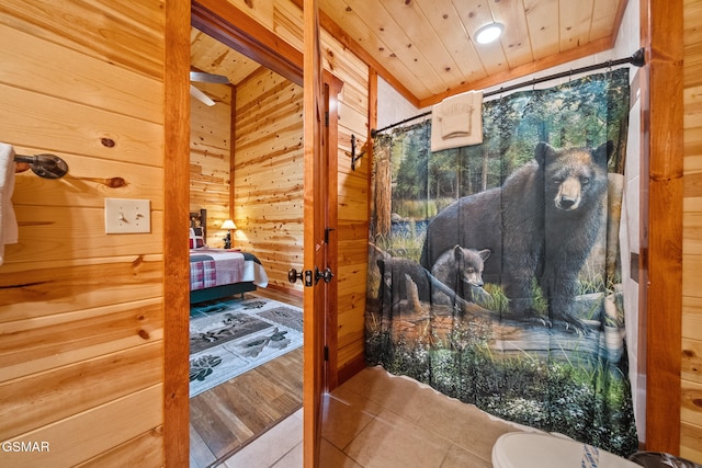 bathroom with wood walls, wood ceiling, tile patterned floors, and toilet