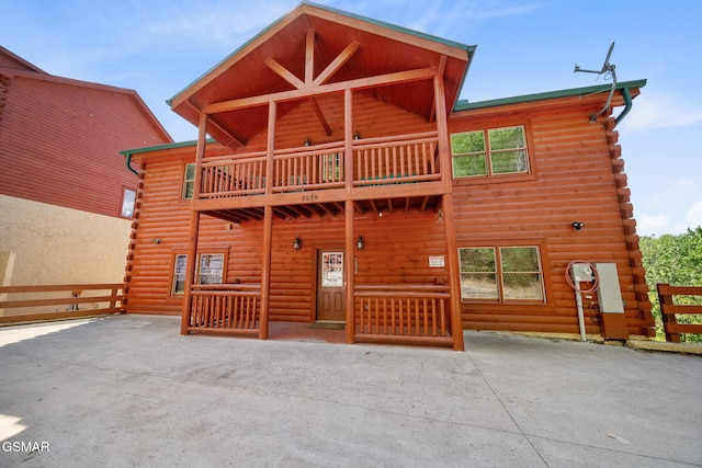 view of front of property featuring fence, a balcony, and log siding