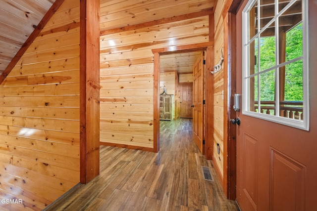 hallway with visible vents, wood walls, wood finished floors, and wooden ceiling