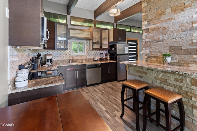 kitchen featuring sink, appliances with stainless steel finishes, dark brown cabinets, beamed ceiling, and light wood-type flooring